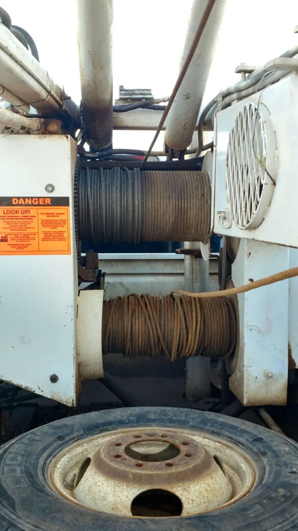 The winch drums of the pump hoist truck, wound with cable and well wire